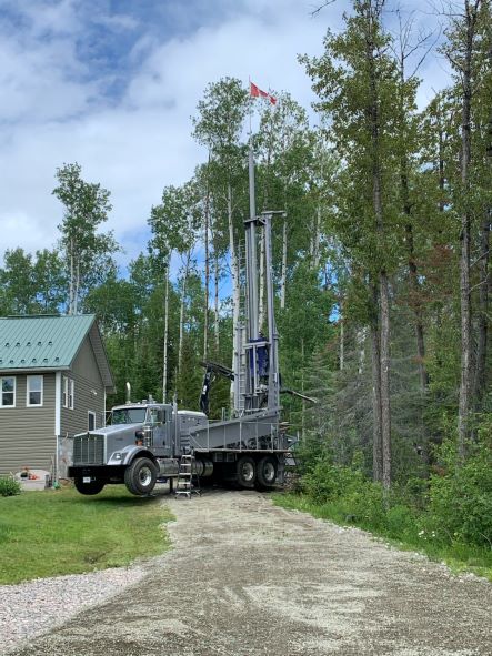 Packard Well Drilling rig drilling a new water well at a rural home in the Temiskaming District, with a Canadian flag flying from the mast